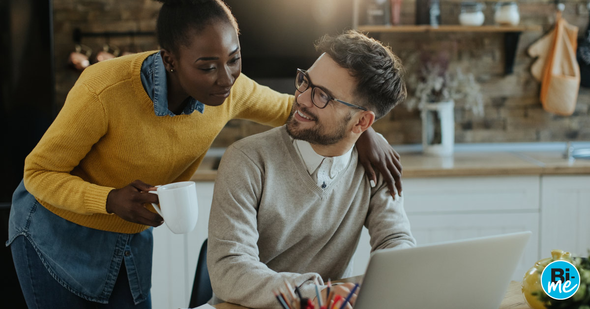 A man and a women smiling while looking at a laptop