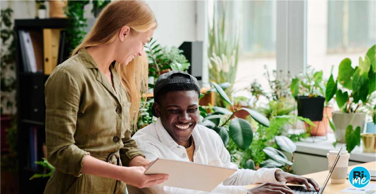 A man and a women smiling while looking at a piece of paper