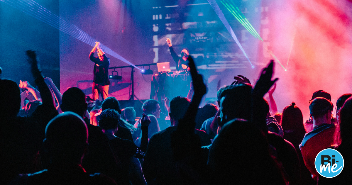 An image of a crowd of people at a concert holding their phones up and looking at the stage