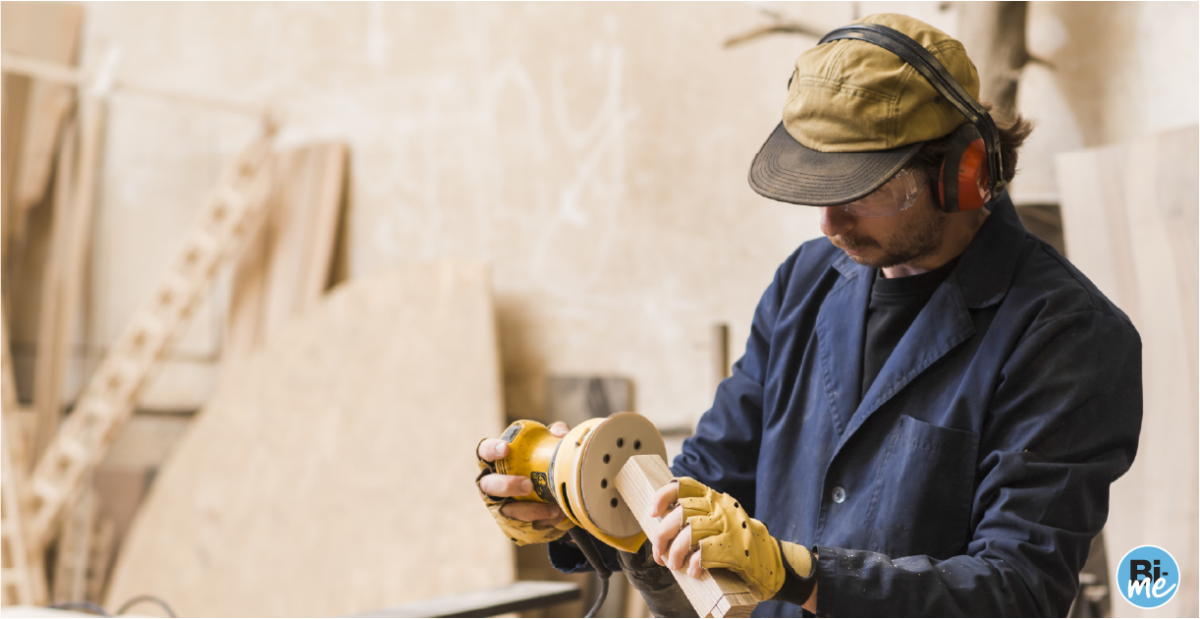 A man with a hat sanding down a piece of wood